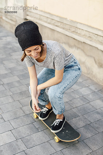 Lächelnde junge Skateboarderin auf ihrem Skateboard