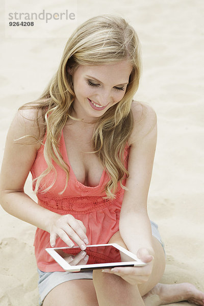 Porträt einer jungen Frau mit digitalem Tablett am Strand