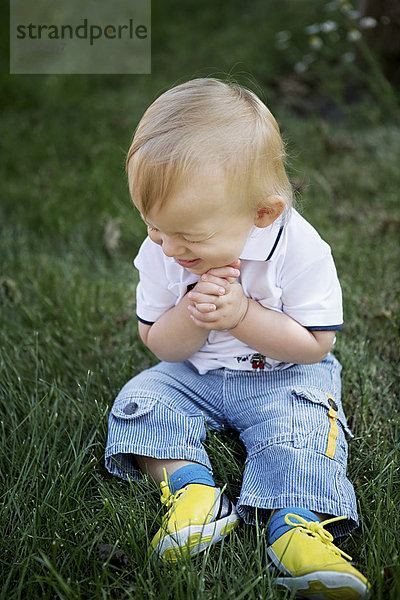 Deutschland  Oberhausen  Blonder Junge sitzend auf Gras im Park