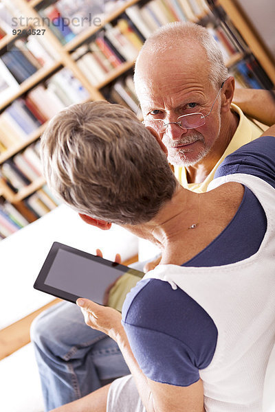 Seniorenpaar auf der Couch sitzend mit digitalem Tablett
