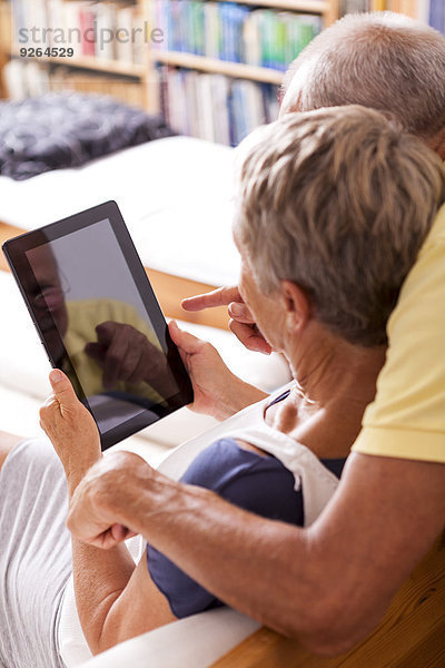 Seniorenpaar auf Couch sitzend mit digitalem Tablett  Teilansicht