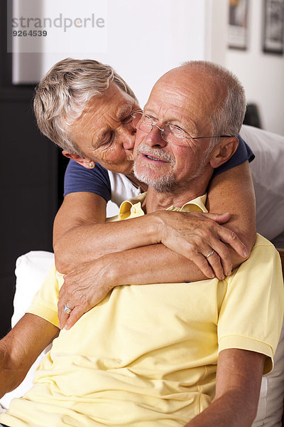 Seniorin  die ihren Mann umarmt und küsst.