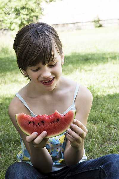 Lächelndes Mädchen beim Essen einer Wassermelone im Garten