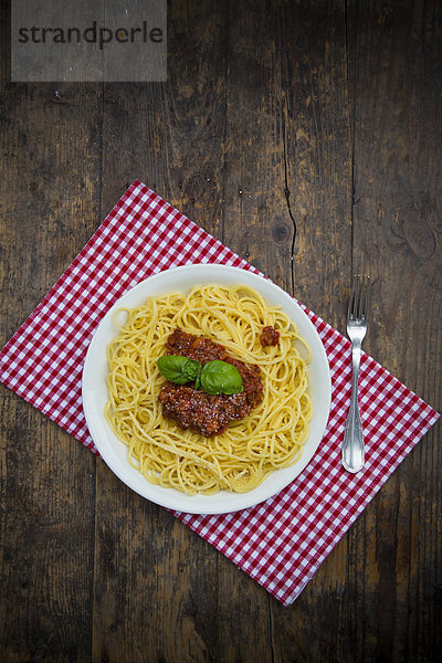 Teller Spaghetti Bolognese  Gabel und Tuch auf dunklem Holz  erhöhte Ansicht