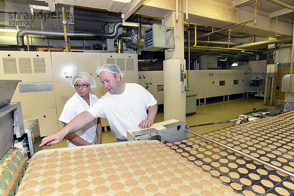 Deutschland  Sachsen-Anhalt  zwei Arbeiter an der Produktionslinie mit Keksen in einer Backfabrik