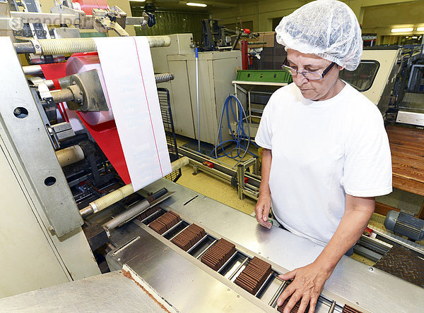 Deutschland  Sachsen-Anhalt  Frau steuert Verpackungsmaschine in einer Backfabrik