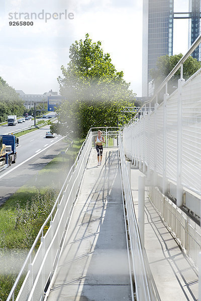 Deutschland  München  Joggerin beim Laufen auf einer Brücke