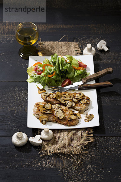Gebratenes Schnitzel mit Champignons und Salat auf dem Teller