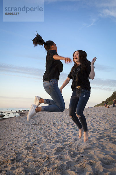 Deutschland  Rügen  Zwei junge Freundinnen beim Springen am Strand