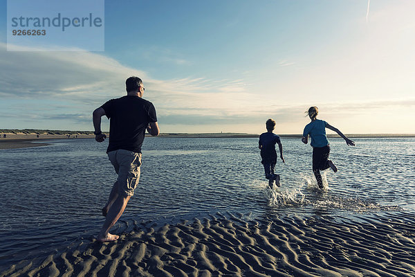 Niederlande  Ouddorp  Vater mit Kindern  die am Strand laufen