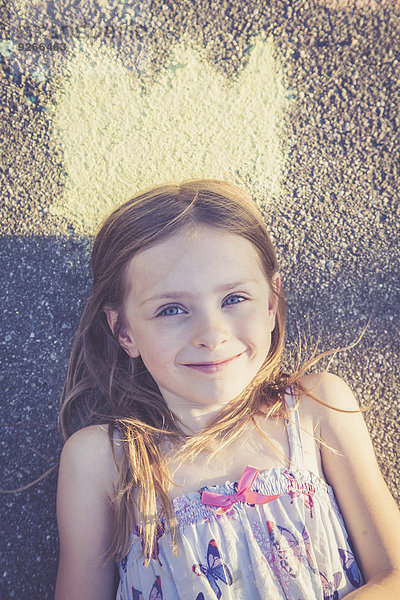 Porträt eines lächelnden Mädchens auf Asphalt mit bemalter Krone