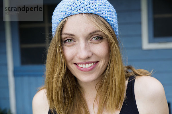 Porträt einer lächelnden jungen Frau mit hellblauer Haube