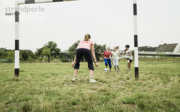 Vier Teenager-Mädchen spielen Fußball auf einem Fußballplatz