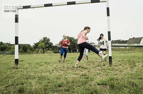 Vier Teenager-Mädchen spielen Fußball auf einem Fußballplatz