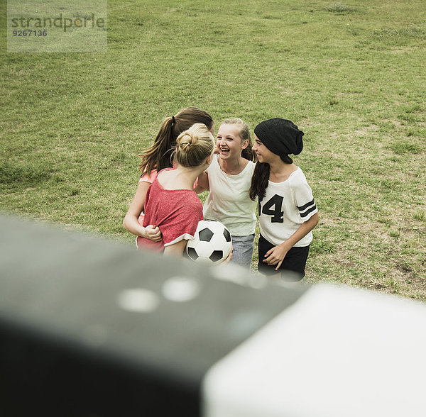 Vier weibliche Teenager-Freunde  die sich auf einem Fußballfeld amüsieren.