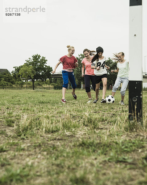 Vier Teenager-Mädchen spielen Fußball auf einem Fußballplatz