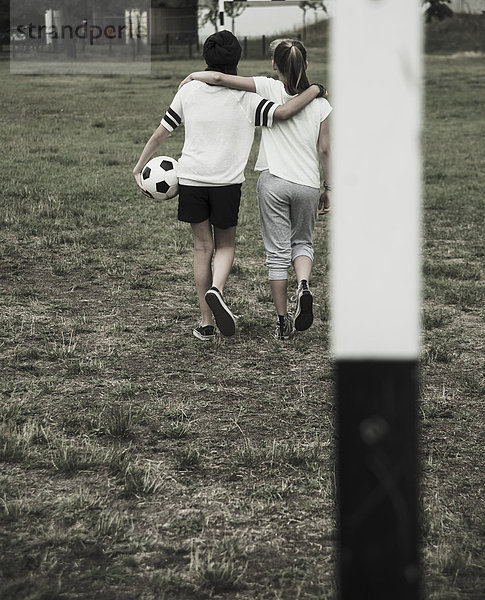 Zwei Teenager-Mädchen auf einem Fußballplatz  Rückansicht