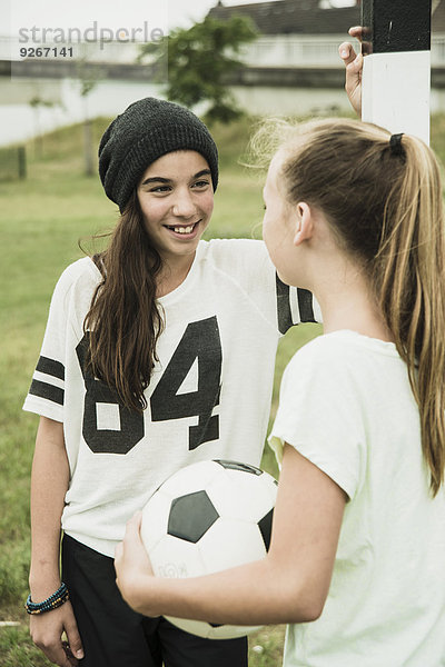 Zwei Teenager-Mädchen kommunizieren auf einem Fußballplatz