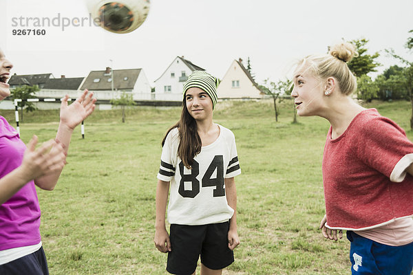 Drei Teenager-Mädchen spielen Fußball auf einem Fußballplatz