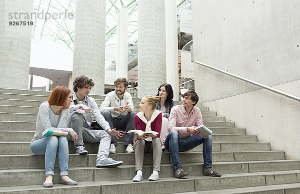 Studentengruppe mit Büchern auf der Treppe sitzend