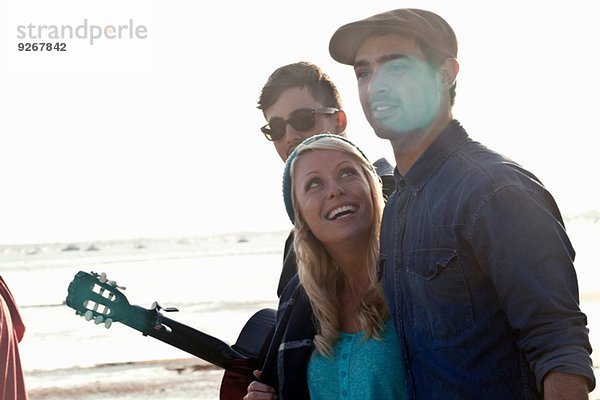 Drei erwachsene Freunde mit akustischer Gitarre am Bournemouth Beach  Dorset  UK