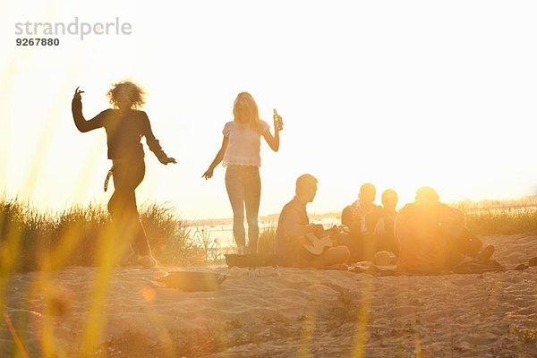 Sechs erwachsene Freunde feiern bei Sonnenuntergang am Bournemouth Beach  Dorset  UK