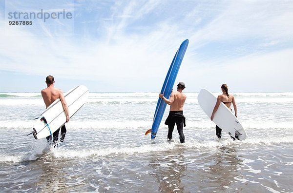 Männliche und weibliche Surferfreunde mit Surfbrettern im Meer stehend
