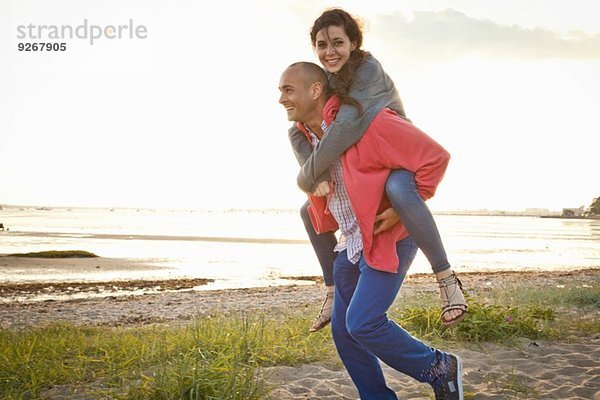 Mann beim Huckepackfahren mit Frau am Strand