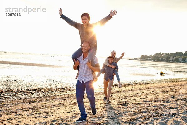 Männer beim Huckepackfahren für Frauen am Strand