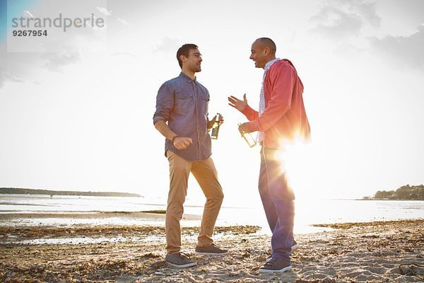 Männer trinken Bier und plaudern am Strand