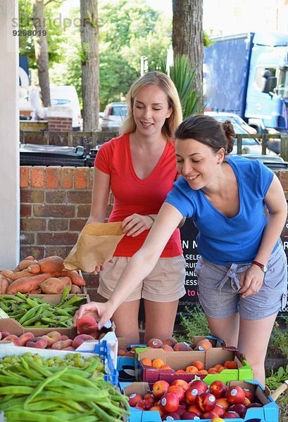 Zwei junge Frauen wählen Obst am Marktstand