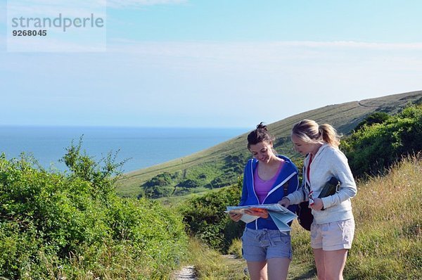 Zwei junge Frauen auf dem Küstenweg mit Karte