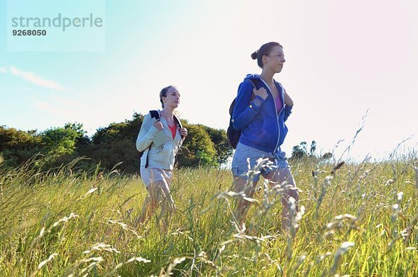 Zwei junge Frauen wandern durchs Feld