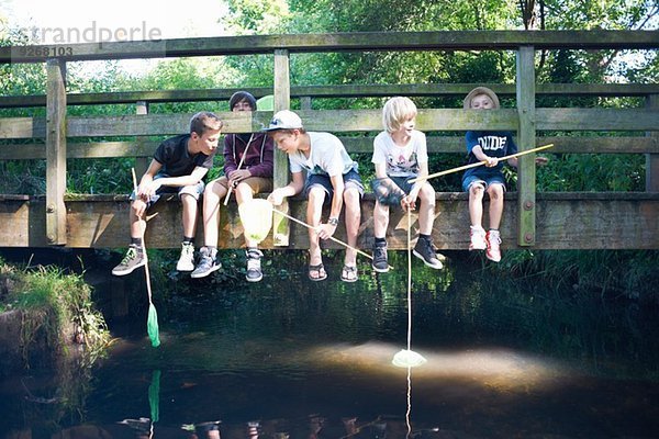 Jungen sitzen auf der Brücke  angeln