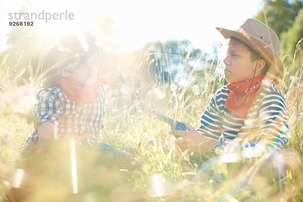 Zwei kleine Jungen als Cowboys verkleidet  die Spielzeugpistolen halten.