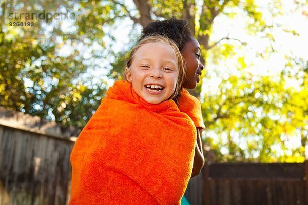 Zwei Mädchen in orangefarbenes Handtuch gewickelt im Garten