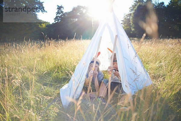 Zwei kleine Jungen sitzen in einem Tipi.