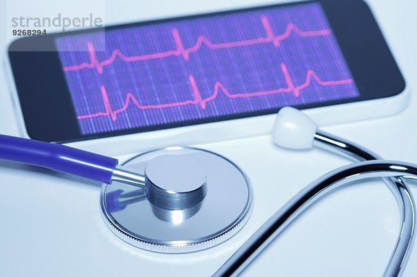 Akustisches Stethoskop und Smartphone-Bildschirm mit einem Elektrokardiogramm