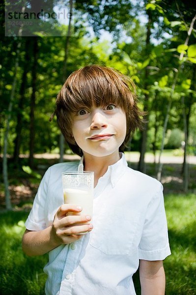 Junge im Wald trinkt Milchshake und zieht ein Gesicht