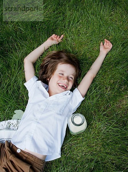 Junge auf Gras liegend  lachend