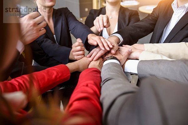 Über-Schulter-Ansicht einer Gruppe von Geschäftsfrauen und Männern mit den Händen im Kreis