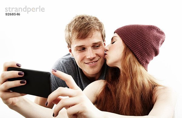 Studio-Porträt eines jungen Paares  das Selfie auf dem Smartphone nimmt.