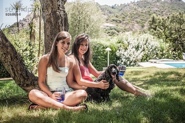 Portrait von zwei Freundinnen mit Hund im Ferienhausgarten  Capoterra  Sardinien  Italien
