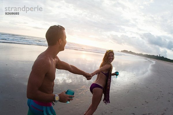 Mittlere erwachsene Frau führt Freund von Hand am Strand  Nosara  Guanacaste  Costa Rica