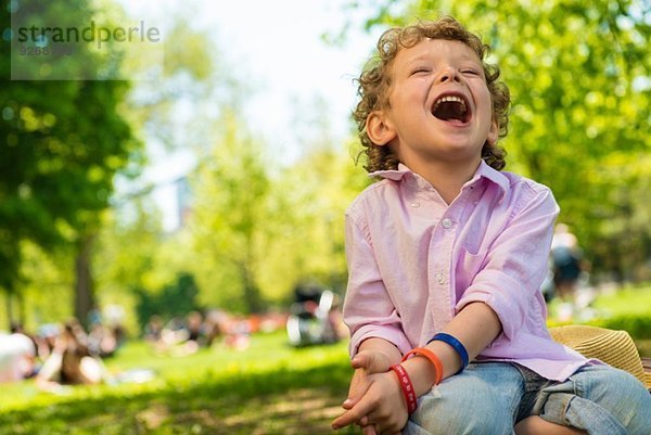 Junge sitzend lachend im Park