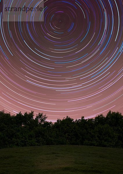 Kreise von Sternenpfaden über ländlichem Feld bei Nacht