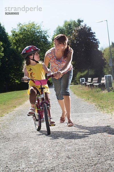 Junges Mädchen lernt Fahrrad fahren mit Mutter