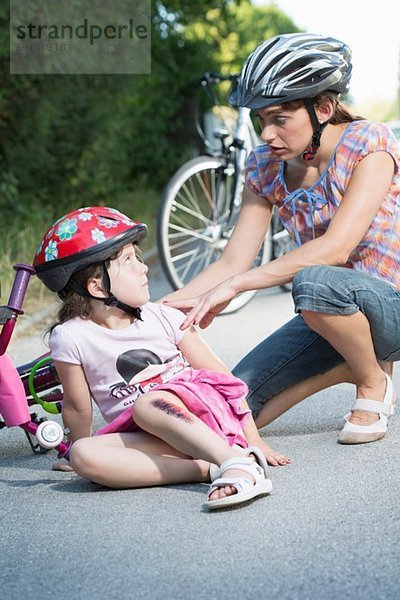 Mutter kümmert sich um Tochter vom Fahrrad gefallen