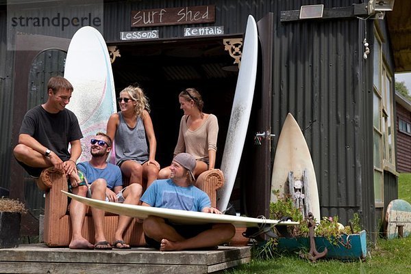 Fünf junge erwachsene Surferfreunde beim Plaudern vor dem Schuppen