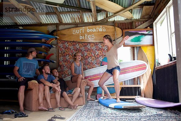 Fünf junge erwachsene Surfer-Freunde  die im Surf-Schuppen herumalbern.